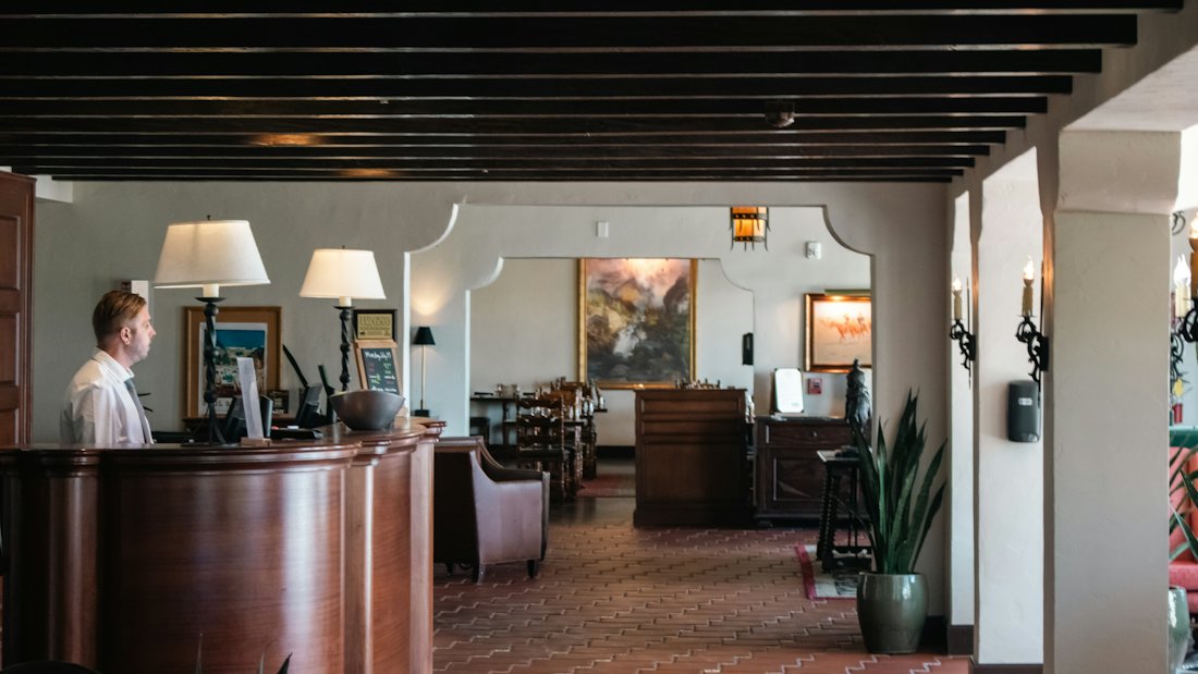 La reception di un albergo con il banco in legno e un addetto di profilo